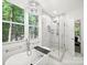 Bright bathroom featuring soaking tub, glass-enclosed shower, and large window with wooded views at 9712 Worley Dr, Charlotte, NC 28215