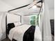 Modern bedroom features a four poster bed with canopy and soft, natural light from a window at 9712 Worley Dr, Charlotte, NC 28215