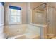 Bright bathroom featuring a soaking tub, glass shower enclosure, and a window providing natural light at 1066 Iveywood Nw Pl, Concord, NC 28027