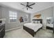 Bright bedroom with a ceiling fan, two windows, and a comfortable bed featuring a wooden North Carolina art piece at 11216 Preservation Ln, Charlotte, NC 28278