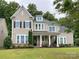 Charming two-story home featuring neutral siding, black shutters, inviting front porch, and manicured landscaping at 11216 Preservation Ln, Charlotte, NC 28278