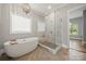 Bright bathroom featuring a soaking tub, glass shower, and modern fixtures under an elegant chandelier at 1152 Grand Oak Dr, Waxhaw, NC 28173