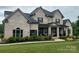 Charming brick home showcases a covered porch, symmetrical design, and verdant lawn enhancing its traditional appeal at 1152 Grand Oak Dr, Waxhaw, NC 28173