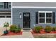 Home featuring a black front door, manicured landscaping, mulched flower beds, and blue siding at 116 Crownpiece St, Troutman, NC 28166
