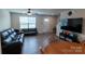 Open-concept living room with hardwood floors, neutral walls, a ceiling fan, and modern black furniture at 116 Crownpiece St, Troutman, NC 28166