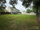 Wide backyard boasts healthy grass, a wooden fence, and a patio with seating under an umbrella at 12517 Pine Terrace Ct, Charlotte, NC 28273