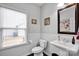 Cozy bathroom with white wainscoting, pedestal sink, and a window that provides natural light at 12517 Pine Terrace Ct, Charlotte, NC 28273