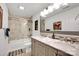 Well-lit bathroom features a double sink vanity with a marble countertop and a tub with tiled walls at 12517 Pine Terrace Ct, Charlotte, NC 28273