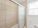Shower with beige tiling, glass door, and bright natural light at 1320 Hartford Ave, Charlotte, NC 28209