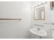 Clean half bathroom featuring a pedestal sink, glass shelves, and a simple mirror with vanity lighting at 1320 Hartford Ave, Charlotte, NC 28209