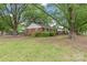 A home's rear exterior features mature trees and an expansive green lawn at 1320 Hartford Ave, Charlotte, NC 28209