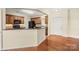 Eat-in kitchen boasts wood cabinets, granite countertops, black appliances, and hardwood floors extending to entry at 14853 Santa Lucia Dr, Charlotte, NC 28277
