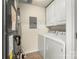 Well-lit laundry room with washer, dryer, white cabinets, and convenient access to mechanical systems at 14853 Santa Lucia Dr, Charlotte, NC 28277
