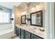 Bathroom boasts dual vanity sinks, framed mirrors, and tub with tile surround at 16425 Spruell St, Huntersville, NC 28078