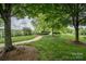 Well-maintained grassy walking path surrounded by mature trees, and a white fence in a tranquil neighborhood at 16425 Spruell St, Huntersville, NC 28078