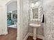 Stylish powder room with pedestal sink, decorative mirror, and patterned wallpaper at 18419 Dembridge Dr, Davidson, NC 28036