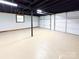 Bright basement area featuring exposed ceiling, painted walls, garage door, and painted floor at 2469 Elkwood Cir, Charlotte, NC 28205