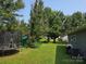 Lush backyard with a swing set, trampoline, and mature trees providing ample shade and privacy at 290 Greentree Dr, Rock Hill, SC 29730