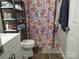 Practical bathroom with a floral shower curtain, storage shelves, and wooden flooring at 290 Greentree Dr, Rock Hill, SC 29730