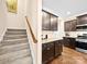 View of a carpeted staircase with a wooden handrail and a kitchen featuring granite countertops and dark cabinets at 5062 Gribble Ln, Lancaster, SC 29720