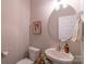 Powder room showcasing a white toilet and stylish vanity with a sink, round mirror, and framed artwork at 5413 Austin Rd # 4, Monroe, NC 28112