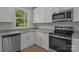 A bright kitchen features white cabinets, stainless steel appliances, and a view from the window at 706 Live Oak St, Shelby, NC 28150