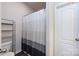 Bathroom with a chrome shelving unit, toilet, and shower stall with a striped shower curtain at 7315 Amberly Hills Rd, Charlotte, NC 28215
