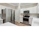 Kitchen with stainless steel appliances, white cabinetry and wood-look flooring at 8744 Barrister Way, Charlotte, NC 28216