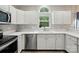 Kitchen featuring stainless steel dishwasher, wood look floors, white cabinetry, and a window at 8744 Barrister Way, Charlotte, NC 28216