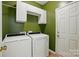Laundry room featuring modern washer and dryer, white cabinets, and green walls at 8744 Barrister Way, Charlotte, NC 28216