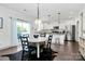 Modern dining area featuring a round table, stylish lighting, and an open-concept view into a kitchen with stainless steel appliances at 8916 Inverness Bay Rd, Charlotte, NC 28278