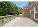 Spacious wooden back deck with a view of a brick house and wooded backyard at 9034 Kensington Forest Dr, Harrisburg, NC 28075