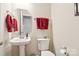 Powder room featuring a pedestal sink and toilet with decorative towels and art at 9034 Kensington Forest Dr, Harrisburg, NC 28075