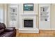 Elegant fireplace with white mantle, built-in shelving, and hardwood floors in the living room at 9034 Kensington Forest Dr, Harrisburg, NC 28075