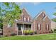 Charming two-story brick home with red shutters, a covered porch, and well-maintained landscaping at 9034 Kensington Forest Dr, Harrisburg, NC 28075