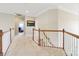 Bright hallway with carpet, wooden railing, and a painting on the wall at 9034 Kensington Forest Dr, Harrisburg, NC 28075