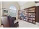 This library features a large bookcase, a window, and a leather chair at 9034 Kensington Forest Dr, Harrisburg, NC 28075
