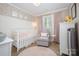 Charming Bedroom with stylish wallpaper, crib, and comfortable seating area bathed in soft, natural light at 127 Leonidas St, Fort Mill, SC 29715