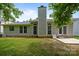 Backyard of home with concrete patio, lush lawn, brick chimney and plentiful windows at 1321 Land Grant Rd, Charlotte, NC 28217