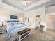 Bedroom featuring a tray ceiling and ensuite bath; also a mirror and side table at 1456 Augustus Beamon Dr, Indian Trail, NC 28079