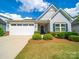 Charming home featuring a two-car garage, blue shutters, and a beautifully landscaped front yard at 1456 Augustus Beamon Dr, Indian Trail, NC 28079