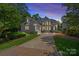 Elegant home featuring a gray facade, well-manicured landscaping, and a spacious driveway leading to an attached garage at 17938 John Connor Rd, Cornelius, NC 28031
