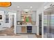 Modern wet bar with custom cabinets, mini-fridge, glass shelving, and elegant mirrored backsplash at 17938 John Connor Rd, Cornelius, NC 28031
