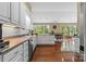 Bright kitchen with white cabinetry, stainless steel appliances, and hardwood floors leading to a dining area with large windows at 1825 Smyre Farm Rd, Newton, NC 28658