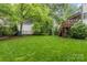 Large grassy backyard featuring a playset, mature trees, and partial fencing at 2414 Bay St, Charlotte, NC 28205
