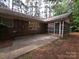 View of a brick home with a screened porch and backyard concrete patio surrounded by trees at 3316 Mckee Rd, Charlotte, NC 28270