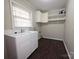 Functional laundry room with white cabinets, shelving, sink, and wood-look flooring at 3316 Mckee Rd, Charlotte, NC 28270