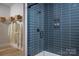 Sleek bathroom with blue tile shower, glass door, and convenient storage shelves at 4209 Pinekirk Dr # 374, Charlotte, NC 28269