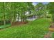 Expansive backyard with a gentle slope, lush lawn, mature trees, and a modern house design at 447 Merwick Cir, Charlotte, NC 28211