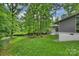 Spacious backyard with lush green grass, mature trees, and a view of the home's exterior at 447 Merwick Cir, Charlotte, NC 28211